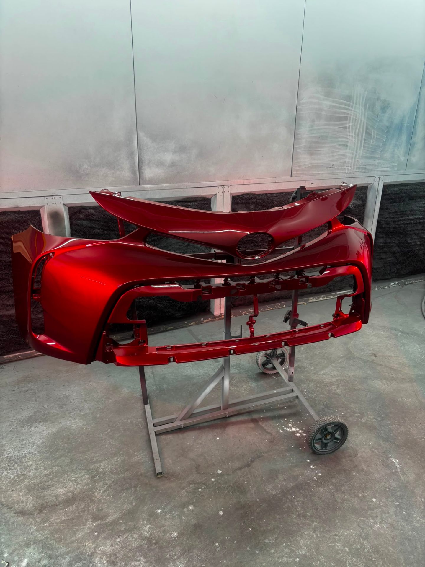 Full paint refinish on a set of Toyota bumpers in metallic red