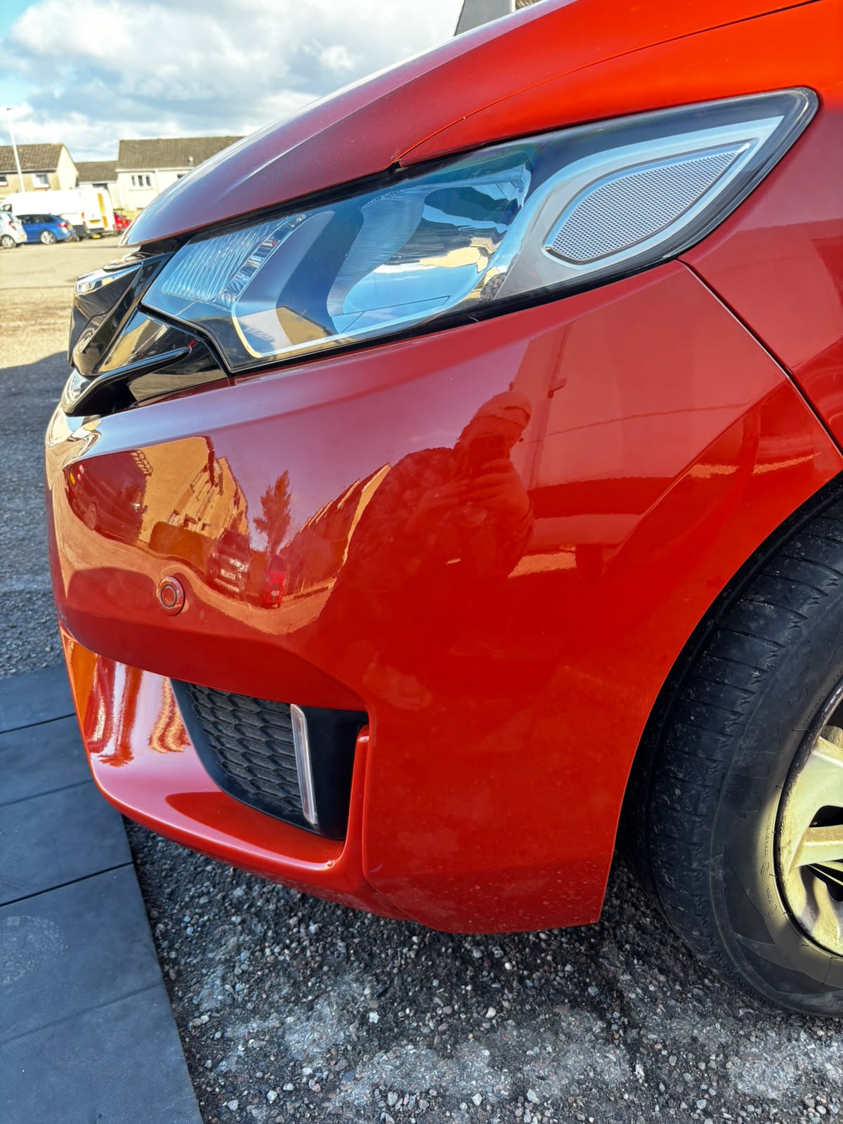 Deep scratch repair polished to a factory finish on a red hatchback